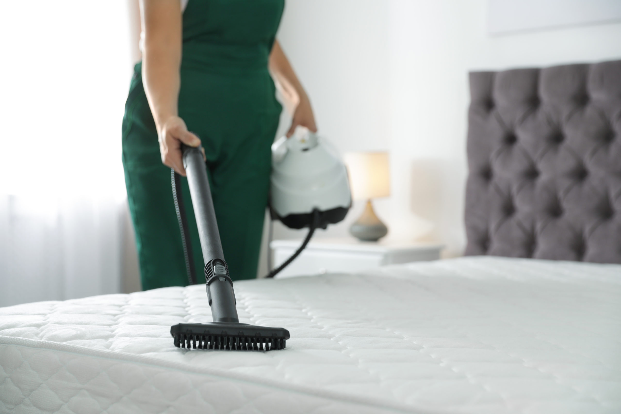 Women Cleaning Mattress with Vacuum Cleaner